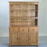 A pine dresser, with a plate rack and drawers and cupboards below,
