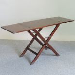 A 19th century style teak coaching table, on a folding stand,