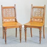 A pair of 19th century light oak hall chairs, with fret carved and tiled backs,