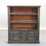 A carved oak dwarf open bookcase, with cupboard below,