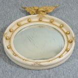 A cream painted and gesso convex wall mirror, surmounted by an eagle,