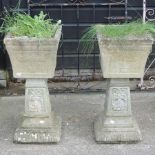 A pair of reconstituted stone planters, on pedestals,