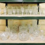 Two shelves of cut glass drinking glasses, bowls and vases,