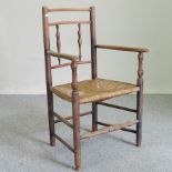 A 19th century elm and rush seated spindle back open armchair