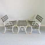 An iron slatted garden bench, together with another similar and a garden table,