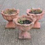 A set of three reconstituted stone terracotta coloured garden urns,