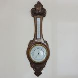 An early 20th century carved oak cased aneroid barometer,