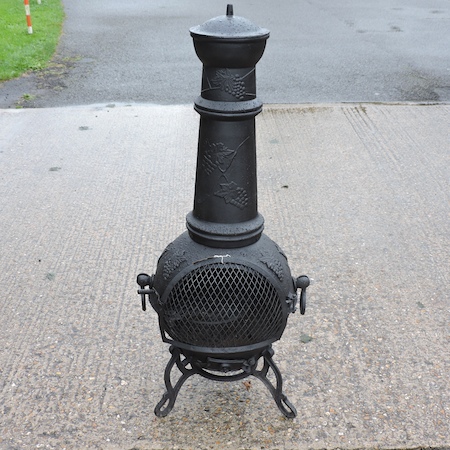 A black painted cast iron chiminea, relief decorated with vines,