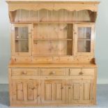 A pine kitchen dresser, the plate rack above an arrangement of drawers and cupboards,