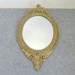 A gilt framed oval wall mirror, with scrolled decoration,