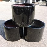 A set of three black painted garden pots,