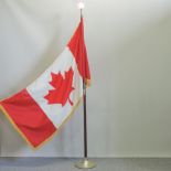 A Canadian flag, on a brass and wood stand,