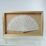 A 19th century pierced ivory fan, in a display frame,