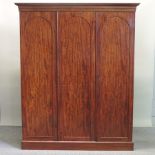 A Victorian flame mahogany triple wardrobe, fitted with slides and drawers, on a plinth base,