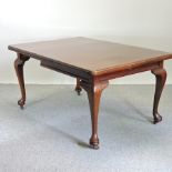 An early 20th century mahogany wind out dining table, with an additional leaf and winder,