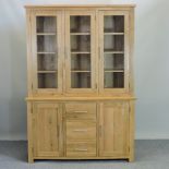 A modern light oak glazed bookcase, with panelled doors below,