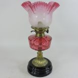 A Victorian cranberry glass oil lamp, with an etched glass shade,