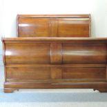 A cherrywood double sleigh bed, with a slatted wooden base,