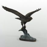 A bronze model of an eagle, shown in mid flight, holding a fish,