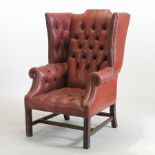 A red upholstered button back wing armchair, on cabriole legs, 130cm high,