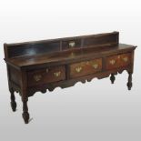 An 18th century and later oak dresser base, containing three short drawers, above a shaped apron,