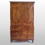 A 19th century mahogany linen press, enclosed by a pair of panelled doors, containing two short,