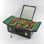 An Art Deco black leather travelling vanity case, the hinged lid inset with a mirror,