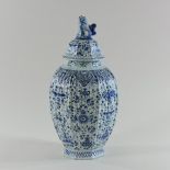 A 19th century Dutch delft blue and white vase and cover, of fluted shape, surmounted by a bird,