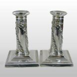 A pair of Victorian silver table candlesticks, with relief decoration, on square stepped bases,