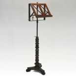 A William IV mahogany adjustable music stand, the adjustable top, with a brass candle holder,