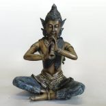 A bronze figure of a Thai Buddha, shown seated playing a pipe,