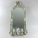 An early 20th century Dresden porcelain framed wall mirror, encrusted throughout with flowers,