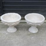A pair of reconstituted stone garden urns, on pedestals,