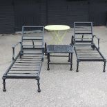 A pair of black metal framed sun loungers, with cream cushions,