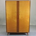 A 1950's Gordon Russell (1892-1980) satinwood and teak double wardrobe, having a fitted interior,