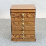An antique pitch pine collector's chest, containing six narrow drawers,