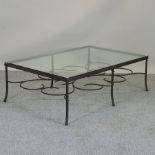 A glass coffee table, on a wrought iron base,