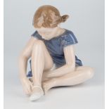 A Royal Copenhagen figure, seated ballet dancer by John Calster, 6.5in. (16.5cm.) high.