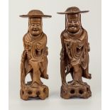 A pair of Oriental carved hardwood figures, with detachable wide brimmed hats, both carrying strings