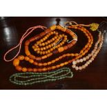 A group of assorted necklaces, comprising three with amber beads, one spinach jade, one graduated