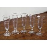 A matched set of five mid-19th century champagne flutes, the plain funnel bowls with basal panel
