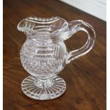 A Georgian cut glass cream jug, baluster form with notch cut rim, prismatic and diamond cut body,