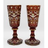 A pair of 19th century Bohemian enamelled ruby glass goblets, the ten sided panel cut flared bowls