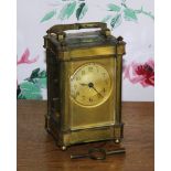 A late 19th century French brass carriage clock, the circular dial with engine turned sun burst