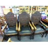 A set of three heavily carved oak throne chairs, with carved mask decoration to backs, black leather