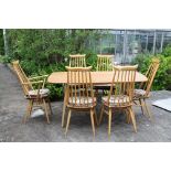 A light elm topped Ercol plank table with six goldsmith chairs.