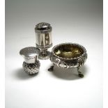 A SILVER SALT CELLAR AND TWO PEPPERETTES the George II style circular salt cellar foliate chased