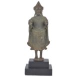 A KHMER BRONZE FIGURE OF BUDDHA, CAMBODIA, CIRCA 12TH CENTURY standing erect on a circular base, his