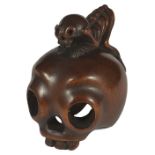 ˜A JAPANESE EBONY NETSUKE OF A SKELETON ON A HUMAN SKULL, EARLY MEIJI PERIOD, CIRCA 1880 the skull