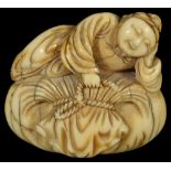 ˜A JAPANESE IVORY NETSUKE OF A BOY ON HOTEI'S SACK, MID EDO PERIOD, CIRCA 1700 leaning on an